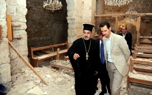 In this photo taken on Sunday, April 20, 2014, and released on the official Facebook page of the Syrian Presidency, Syrian President Bashar Assad, right, checks a damaged church during his visit to the Christian village of Maaloula, near Damascus, Syria.