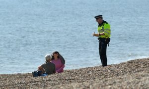 Brighton, UK 10th April 2020 A police officer asks members of the public to leave the beach.